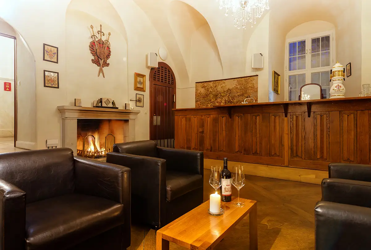 Zámecký bar s krbem a černými koženými křesly